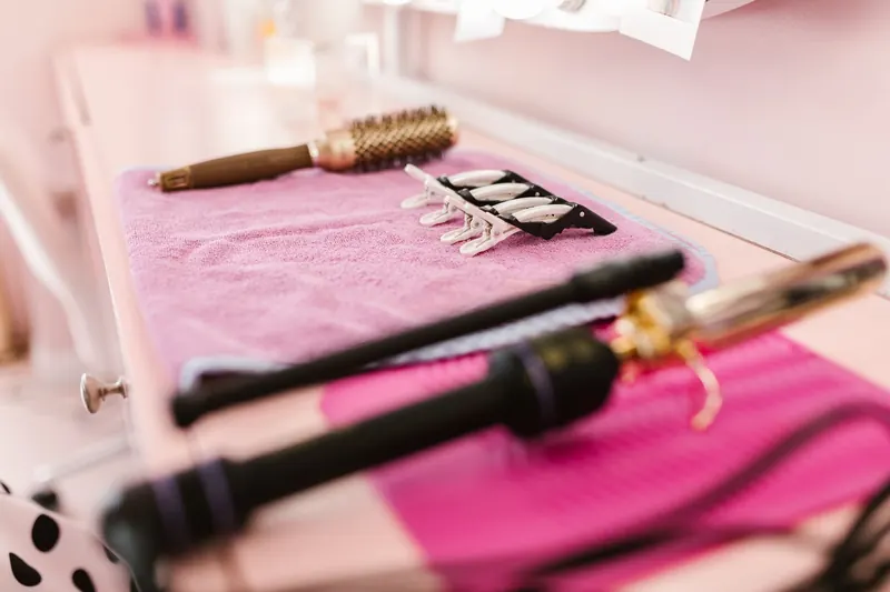 A selection of hair styling tools arranged on a pink towel in a salon setting, ready for use
