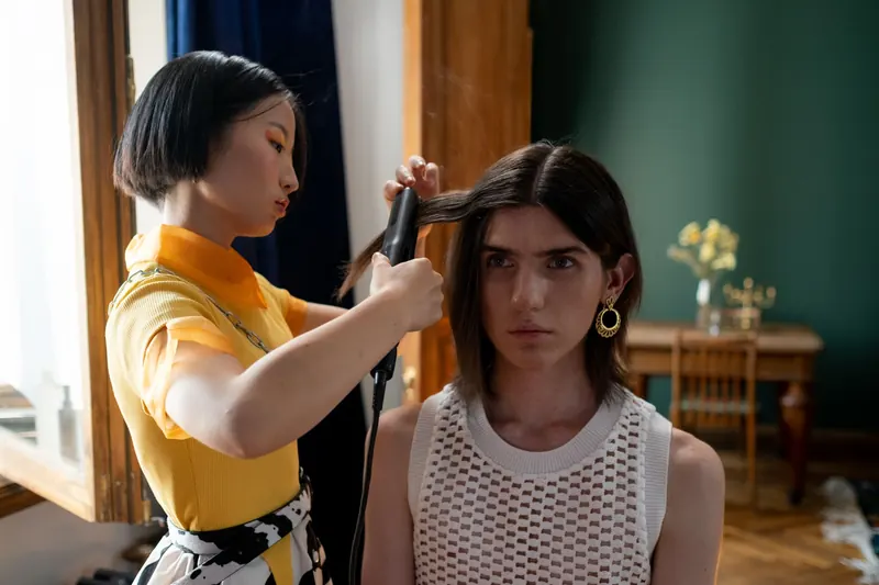A hairdresser styling a client's hair with a flat iron in a contemporary salon setting