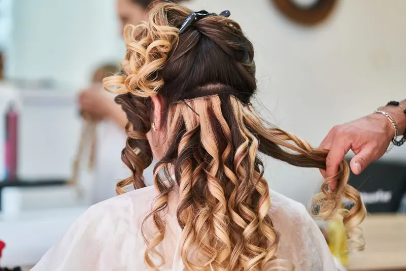 Close-up of hairstylist perfecting curls on a woman's hair in a salon setting