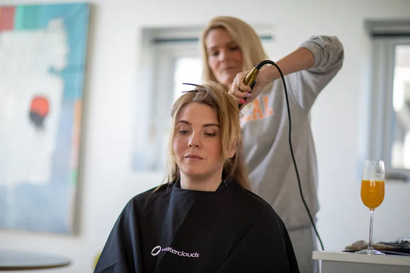 A woman gets her hair styled with a curling iron in a contemporary salon setting