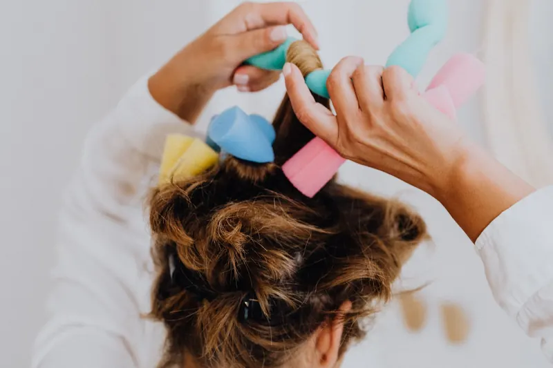 Woman styling hair with soft foam curlers in a close-up view