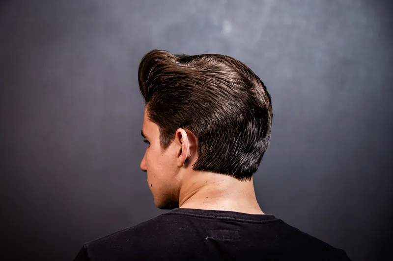 Close-up of a man's stylish hairstyle from the back against a grey background