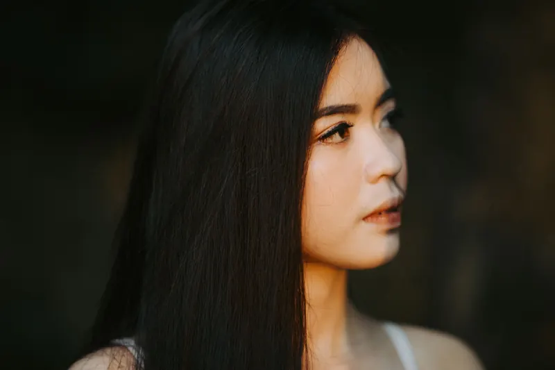 Close-up portrait of a young woman with long straight hair, soft lighting and serene expression